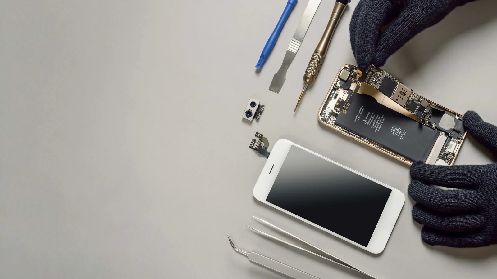 Disassembled phone with repair tools on a workbench
