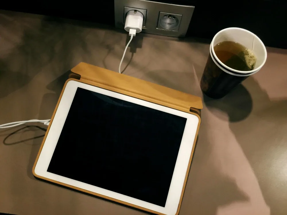iPad plugged into a wall charger on a desk