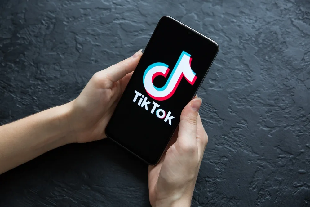 Hands holding a phone with the TikTok app open