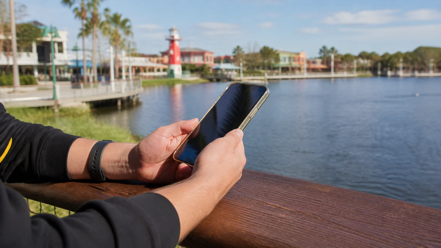 Kissimmee visitor using a repaired smartphone near a Central Florida lakefront